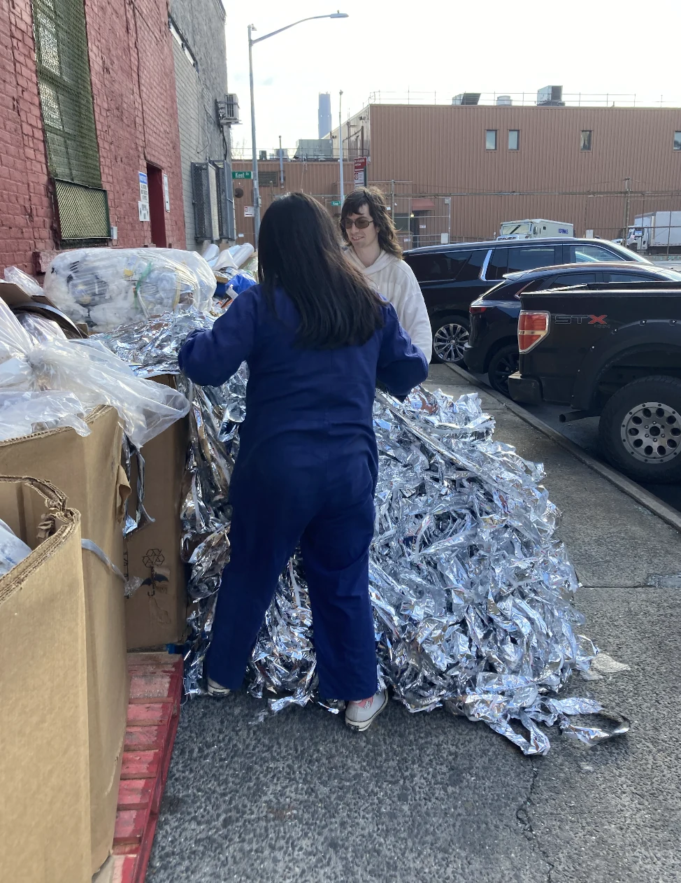 Two people sorting discarded materials on a city street