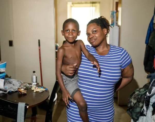 A mother holding her young son in their apartment