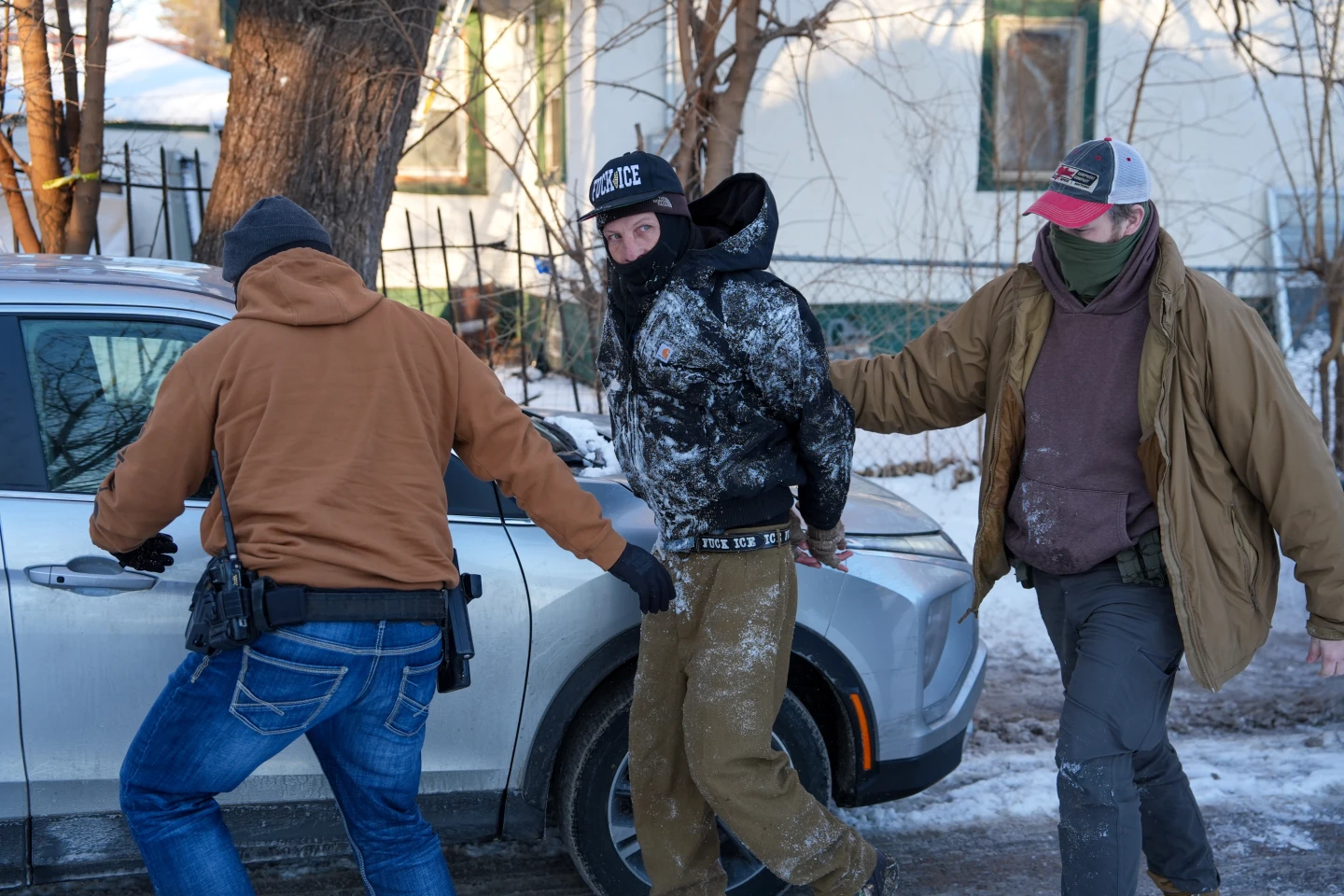Federal agents detaining a person beside a vehicle in Minneapolis